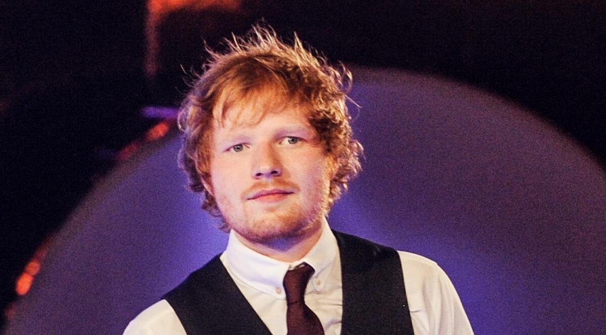 Ed Sheeran menggunakan kemeja putih, vest hitam dan dasi berwarna merah maroon